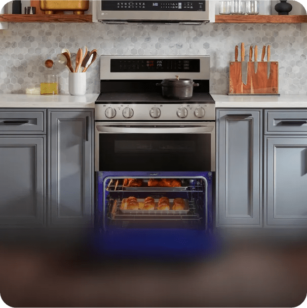 An LG freestanding range bakes a tray of pastries, sitting between cabinets in a modern kitchen.