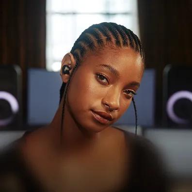 Photo of Willow Smith with LG speakers in the background.