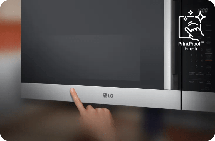 Close-up of an LG microwave with a stainless steel lower trim and black glass door, as a hand touches the front near the LG logo and control panel.