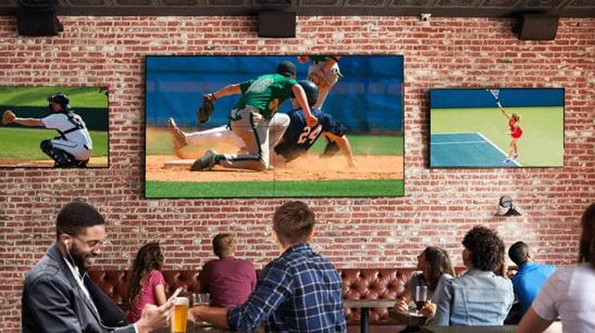 Patrons watch different sports games on LG displays at a restaurant
