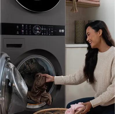 Woman adding laundry to a front-load WashTower washer.