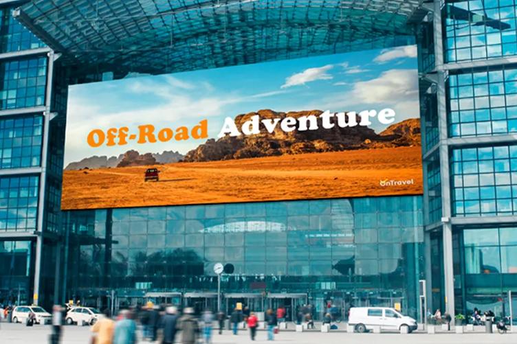 Large billboard on a glass building showing an off-road desert scene with text "Off-Road Adventure."