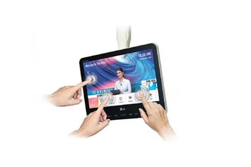 LG touchscreen displaying a news interface with hands interacting with the screen.