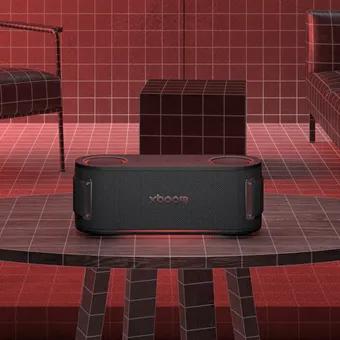 LG XBOOM speaker placed on a table in a red-toned room with grid-patterned walls and modern furniture.