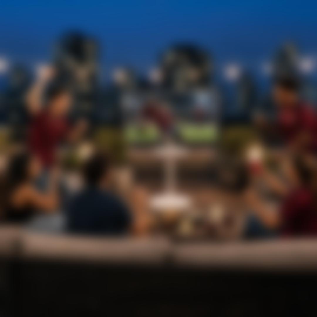 A group of friends cheer as they watch a soccer match celebration on an LG StanbyME 2 and speaker on a city rooftop surrounded by lit buildings. “Game Changers Event 2026” badge. Pop-out text reads “Uber Eats or DoorDash—$50 credit”. 