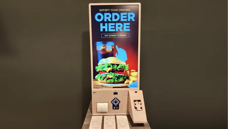 A touch kiosk display in the LG LA Business Innovation Center, advertising a touch screen to order a hamburger meal. 