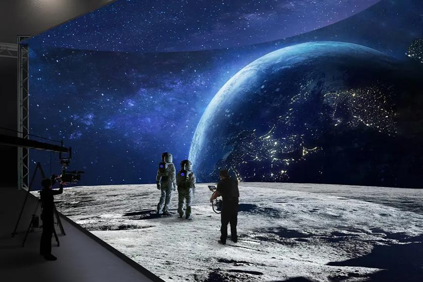 Film set with astronauts on a moon surface and a large screen displaying space and Earth.