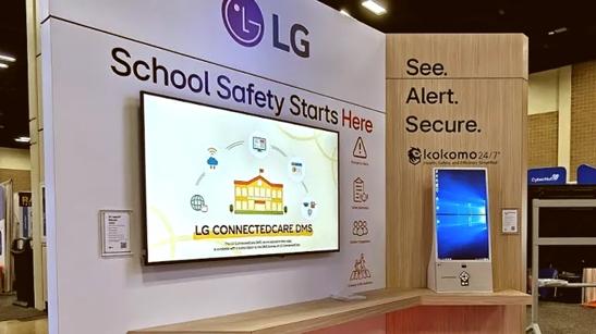 LG Digital Signage mounted in the LG ISTE booth shows a graphic of a school, with the words LG Connected Care DMS under it. Above this display, the LG logo and the words School Safety Starts Here are printed on the booth wall. Diagonally to the digital display is an LG Touch Kiosk with a Windows background. Printed on the booth wall above the kiosk are the words See. Alert. Secure. And the logo of LG's partner Kokomo. 