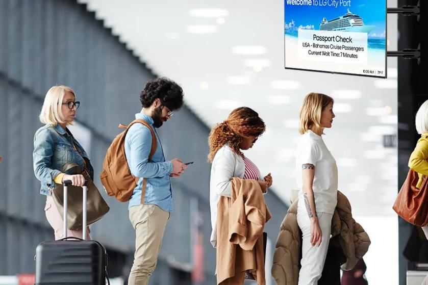 Passengers wait in line in a cruise terminal. LG signage displays vital information overhead.