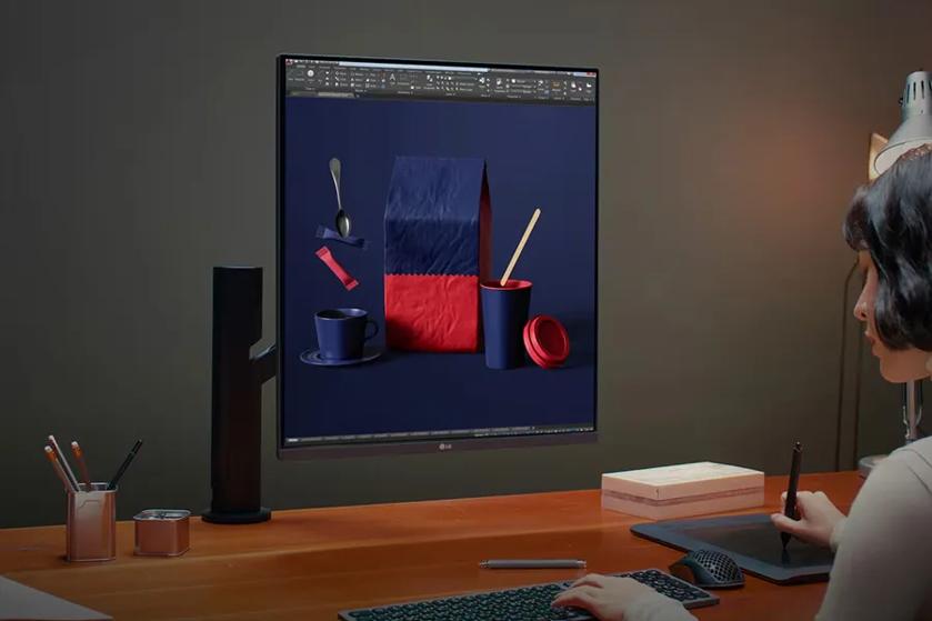 A person using a graphic tablet in front of a monitor displaying a graphic design program.