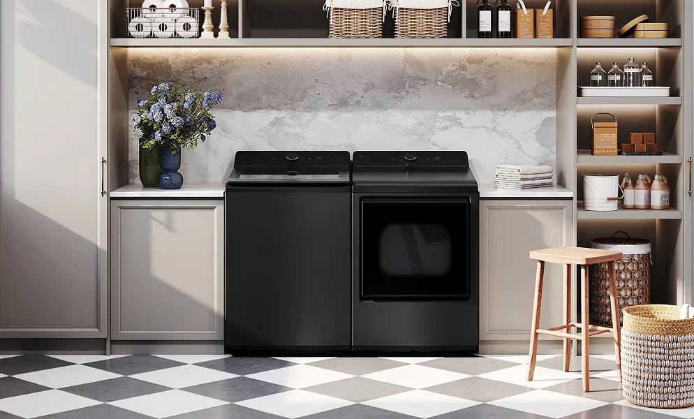 A black LG top load washer and LG front load dryer are in a modern, stone-accented laundry room.
