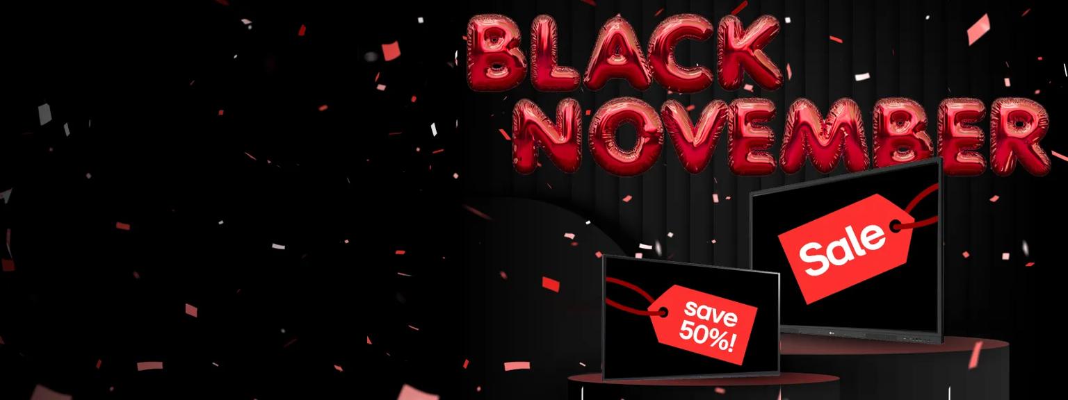 Red balloons shaped like letters spell out 'Black November' on a dark background. Beneath them are two LG digital signage displays, with red sales tags on their screens. One tag reads Sale and the other reads Save 50%! Confetti falls around the scene.