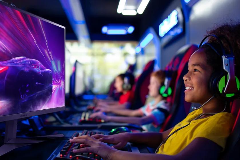 A grade school child grins as they play e-sports on an LG gaming monitor. 