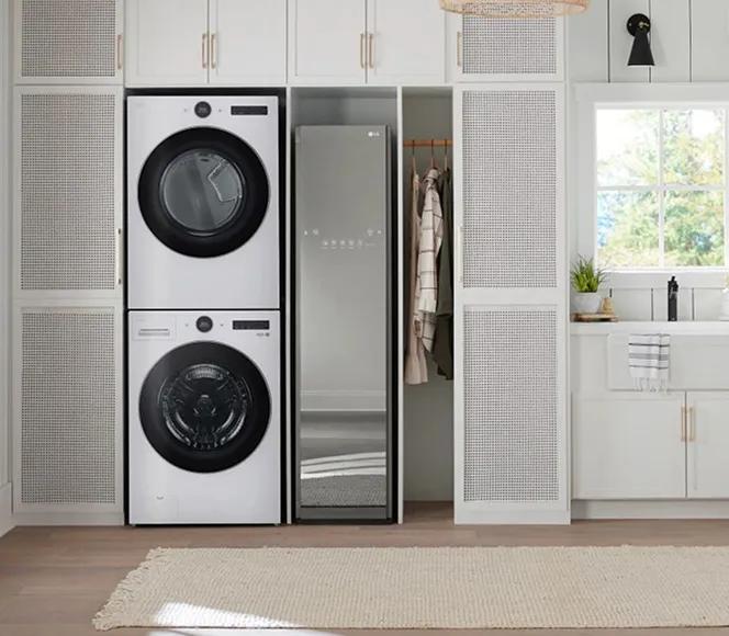 Stacked white front-load washer and dryer next to an LG Styler in a country-style laundry room with white cabinets and walls.