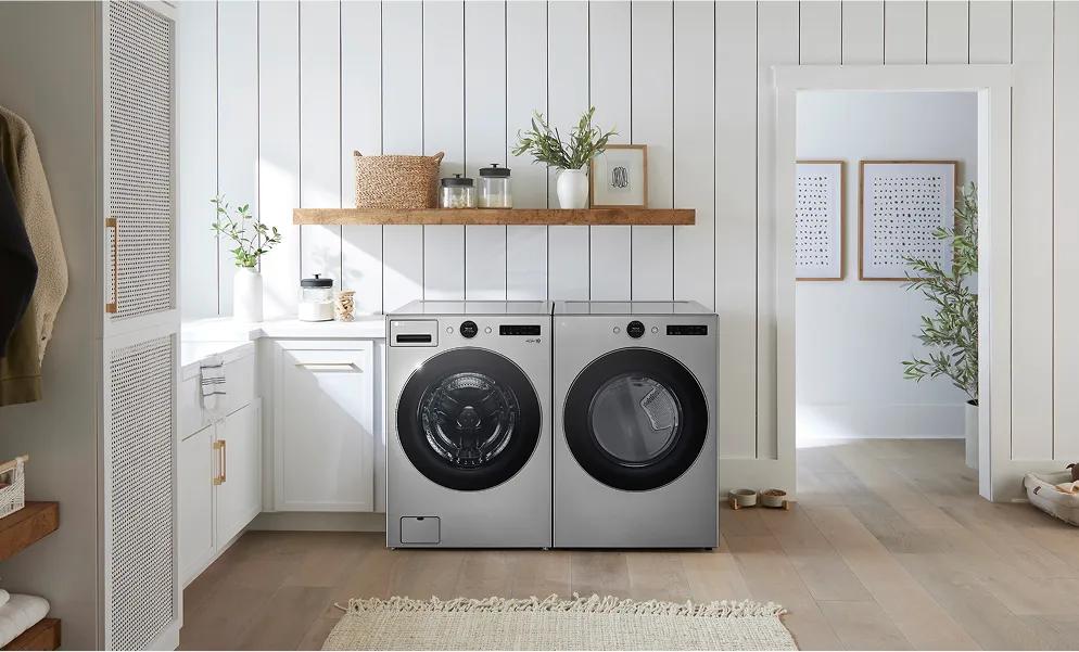 Silver front-load washer and dryer in a bright laundry room white cabinets and walls.