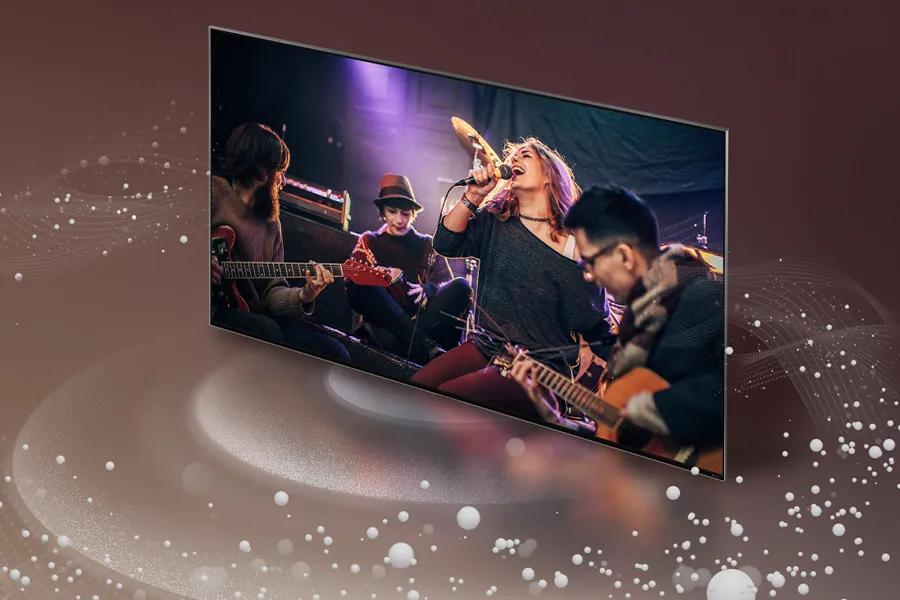 Sound waves emanate from all around an LG QNED99T with the screen featuring a band performing. 