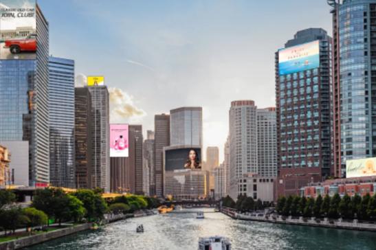 Cityscape with skyscrapers, a river, and electronic billboards.