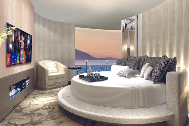 An upscale cruise cabin with a round bed and rounded walls. On the wall, an LG Cruise Cabin TV is mounted and showing the pro:centric SMART menu.