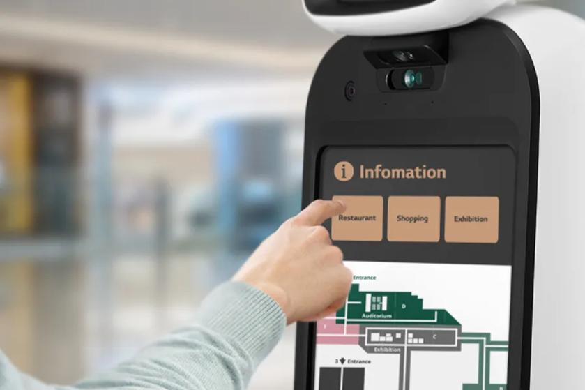A close-up of CLOi's display, showing a map of  a museum or entertainment venue with options for Restaurant, Shopping, and Exhibition. A user's hand is pointing to Restaurant.