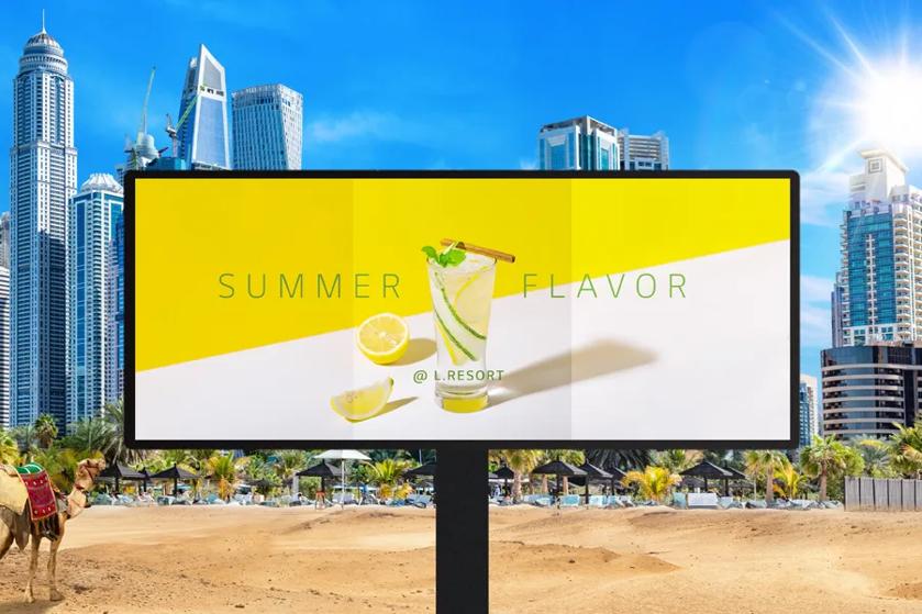 A bright DVLED billboard advertises lemonade in a sandy environment. A city and palm trees are in the background. To the left of the sign is a camel. The DVLED shows three different brightness options on its display. 