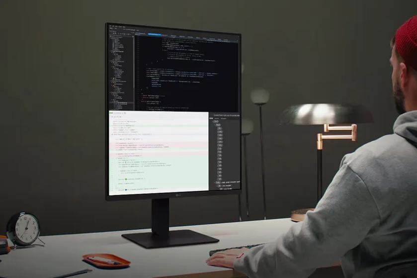 Person at a desk working on a computer with code on the screen.