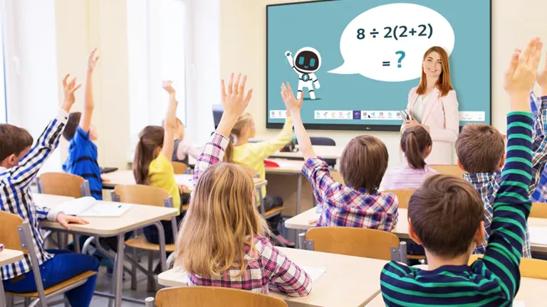 A teacher stands by an LG CreateBoard with a math problem displayed on it. Her class is full of raised hands from eager students.