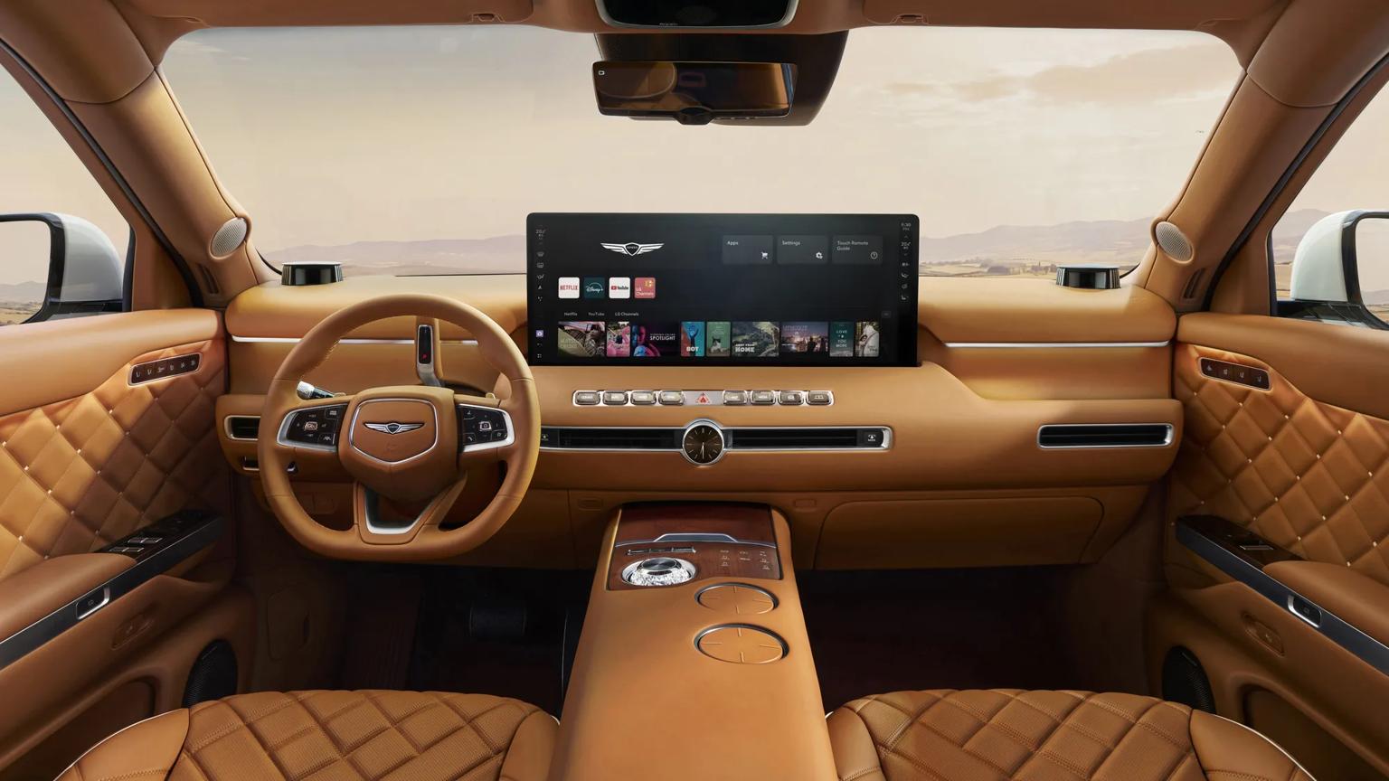 Interior of a luxury Genesis vehicle with tan quilted leather seats and door panels, a wood-trimmed center console, and a wide infotainment screen showing LG webOS with Netflix, Disney+, YouTube, and LG Channels apps.