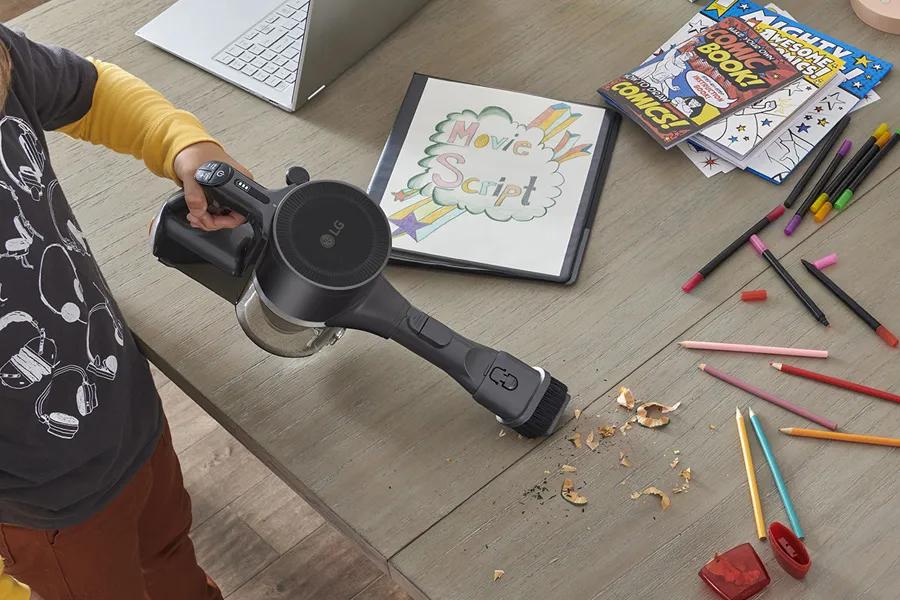 Image of person vacuuming debris on top of a desk using the vacuum in handheld mode