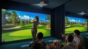 People watch a golfer practicing on a golf simulator with bright, vivid visuals displayed by LG ProBeam projectors.