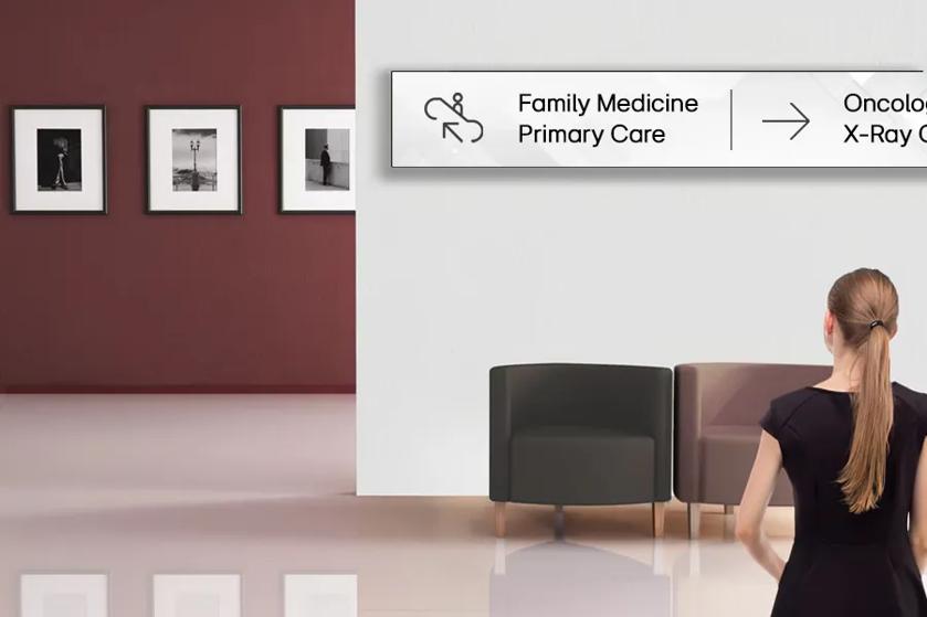 A hospital visitor looks at LG stretch signage on the wall, directing her to various healthcare departments