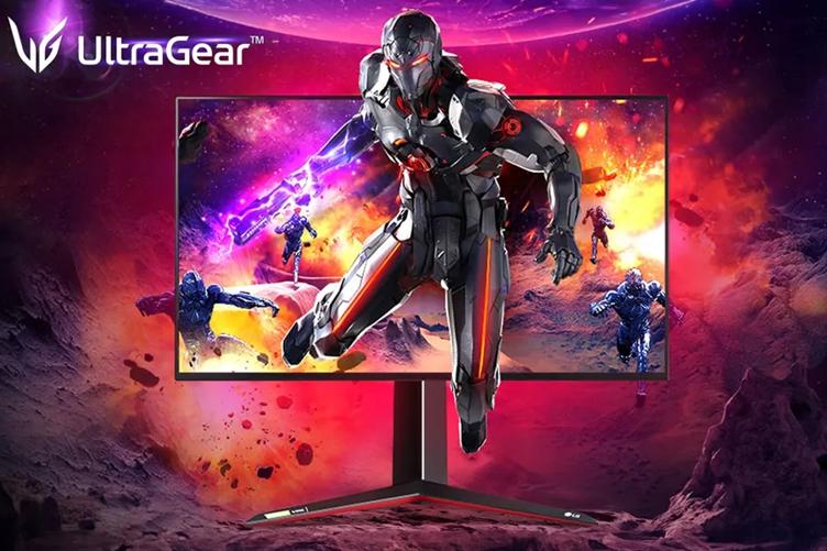 An LG UltraGear gaming monitor on a red and purple space-style background. A figure in futuristic armor is climbing out of the monitor's display,. Other similar figures are on the screen behind him. The UltraGear logo is in the top left corner.