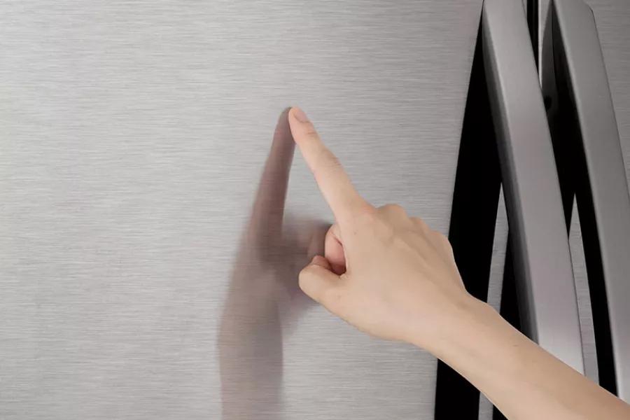 a person touching stainless steel exterior of refrigerator