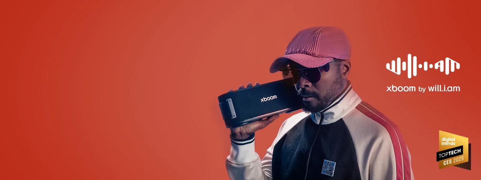 will.i.am holding an xboom speaker on his right shoulder.