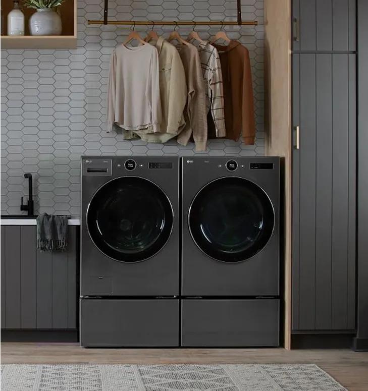 Dark gray front-load washer and dryer in a laundry room with dark gray cabinets.