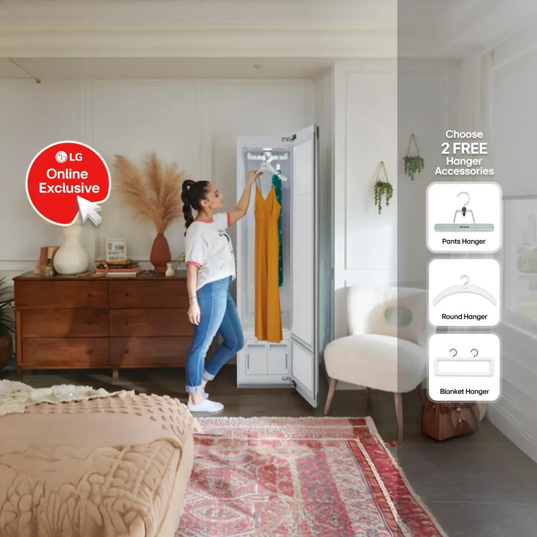 Woman hanging an orange dress inside a built-in LG Styler steam closet in a bright, well-decorated bedroom, with a "LG Online Exclusive" badge on the left. Right side reads "Choose 2 FREE Hanger Accessories," showing Pants Hanger, Round Hanger, and Blanket Hanger options.