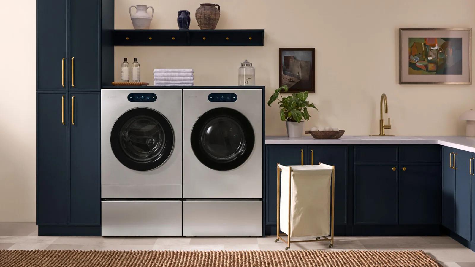 LG Signature front-load washer and dryer in brushed steel with tinted glass doors, installed side by side in modern laundry room.