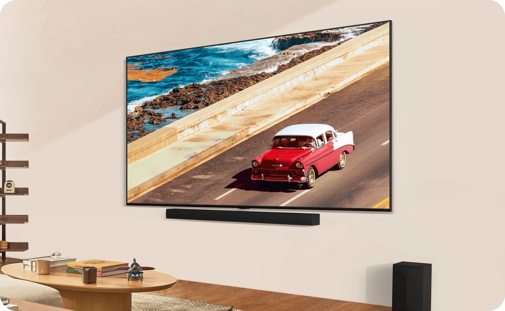 Minimalist space with light walls, wall-mounted LG TV shows red classic car on coastal road, with LG soundbar and subwoofer.
