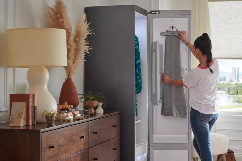 Woman using LG Styler to hang pants to be pressed and restored