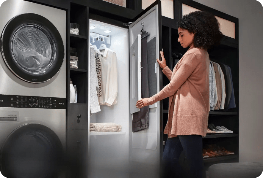 A woman creases a pair of dress pants using the Styler®'s door-mounted pants press.