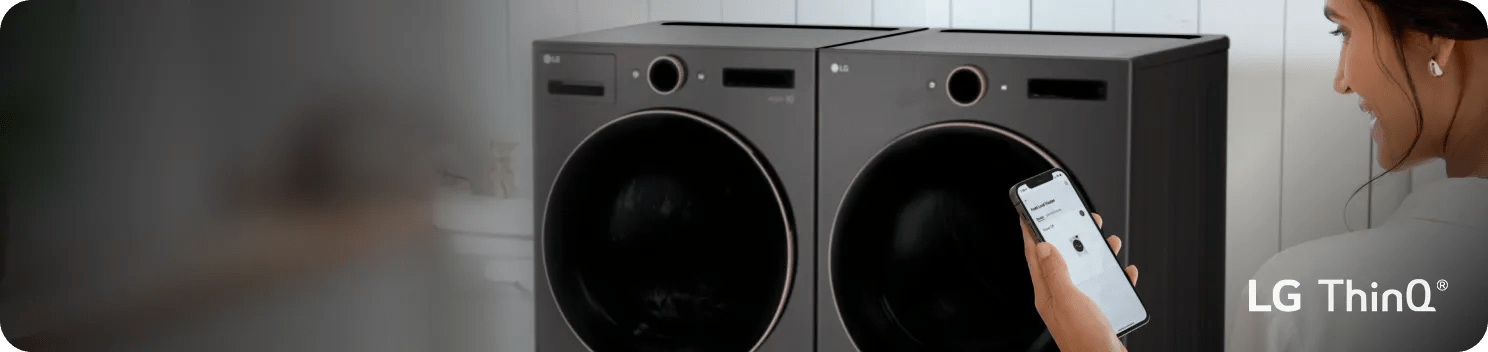 A woman looks at the ThinQ® interface on her smartphone in front of an LG washer and dryer pair.
