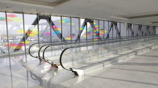 An interior of an airport with transparent LG DVLED on the large windows, displaying colorful fish swimming by.