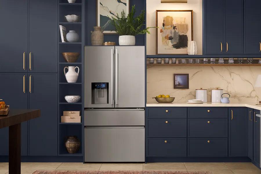 A sleek, four-door stainless steel French door LG refrigerator with an external water dispenser, recessed into navy blue custom cabinetry with gold accents and decorative shelving.
