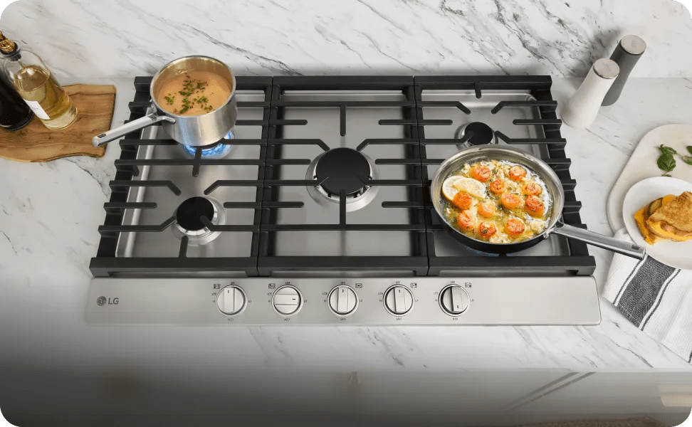 An overhead shot of various pots and pan simmering on the cast iron grates of an LG gas cooktop.