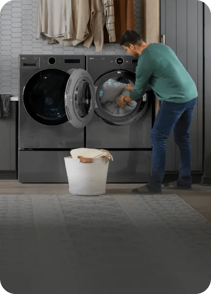 A man unloads an LG front load dryer into a laundry basket on the floor.