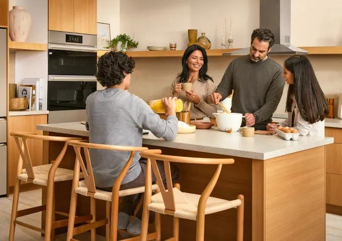 LG SIGNATURE Seamless Collection kitchen with built-in wall oven, family gathered around island preparing breakfast, lifestyle view.