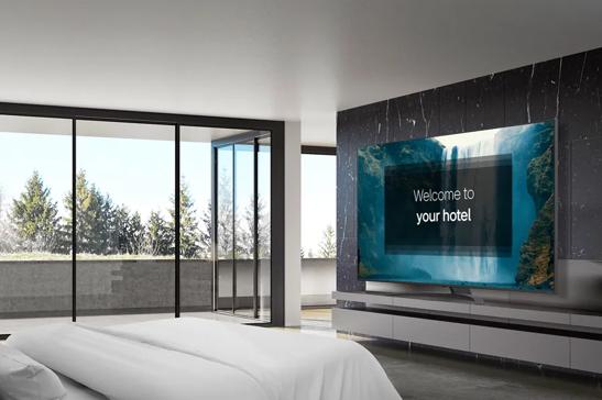 Modern hotel room with a large TV, glass balcony doors, and a view of trees.

Transcribed Text:

Welcome to your hotel