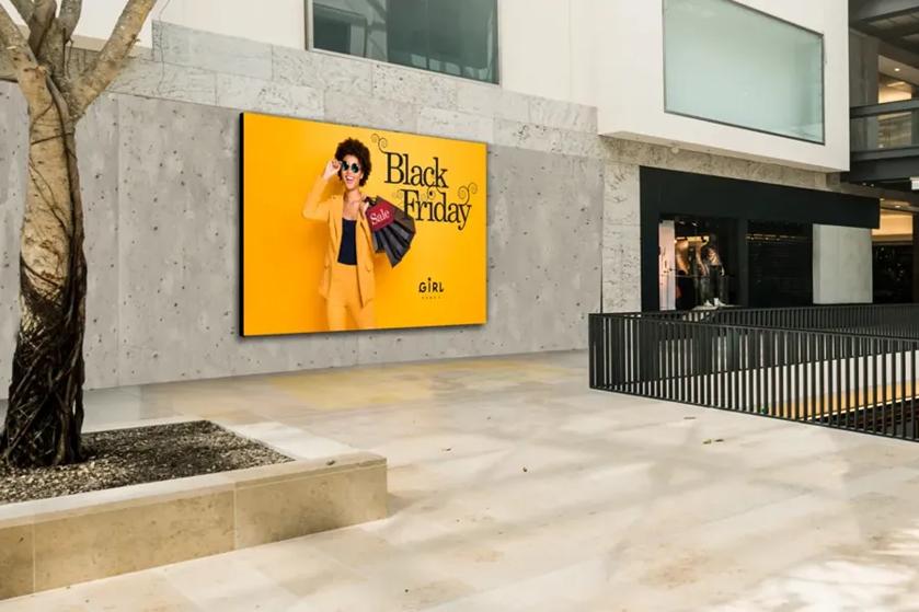 Mall interior with a Black Friday advertisement showing a person in a yellow suit holding shopping bags.