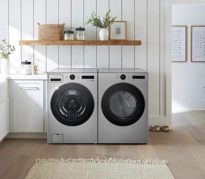 Silver front-load washer and dryer in a bright laundry room white cabinets and walls.