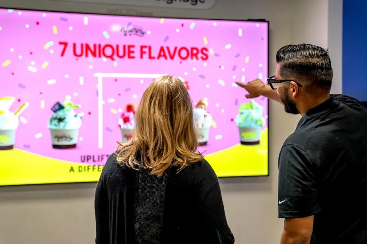 A woman is looking at a brightly colored LG digital display while an LG employee gestures to it.