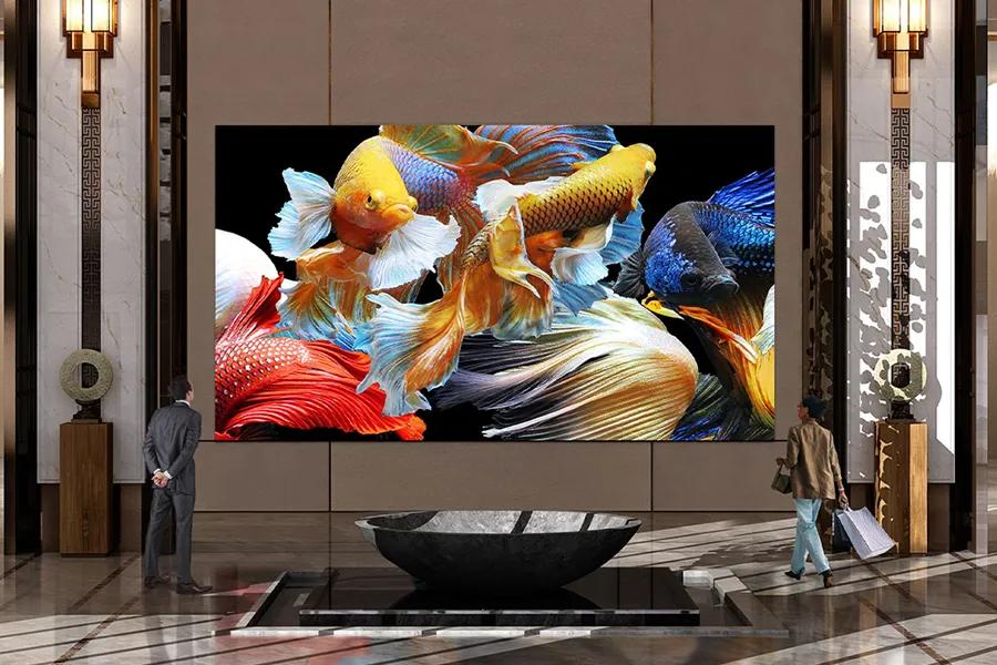 LG DVLED display showing vibrant colorful fish imagery mounted on a wall in an upscale lobby with two people viewing it